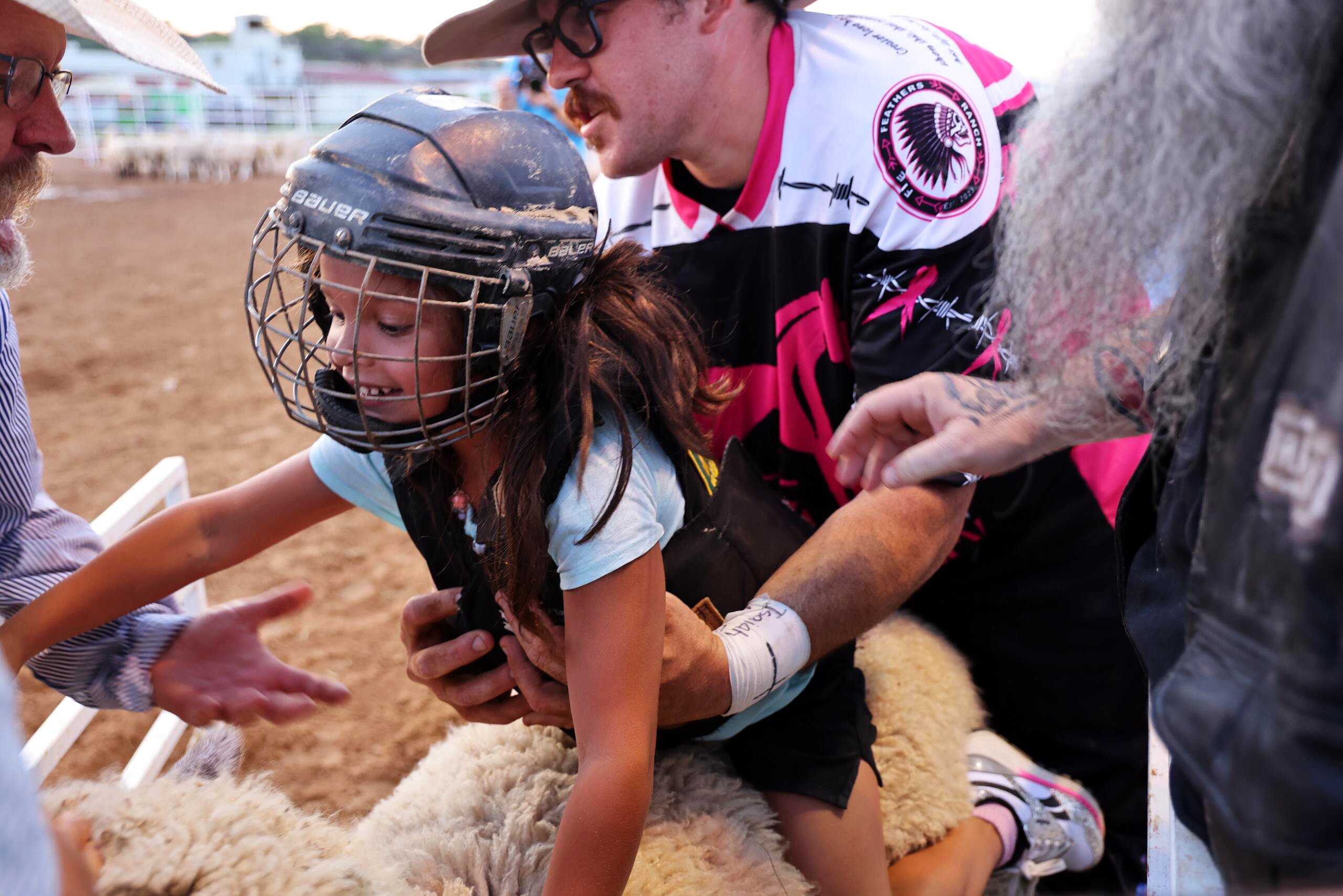 Young rider in protective gear with a team member before a mutton busting ride