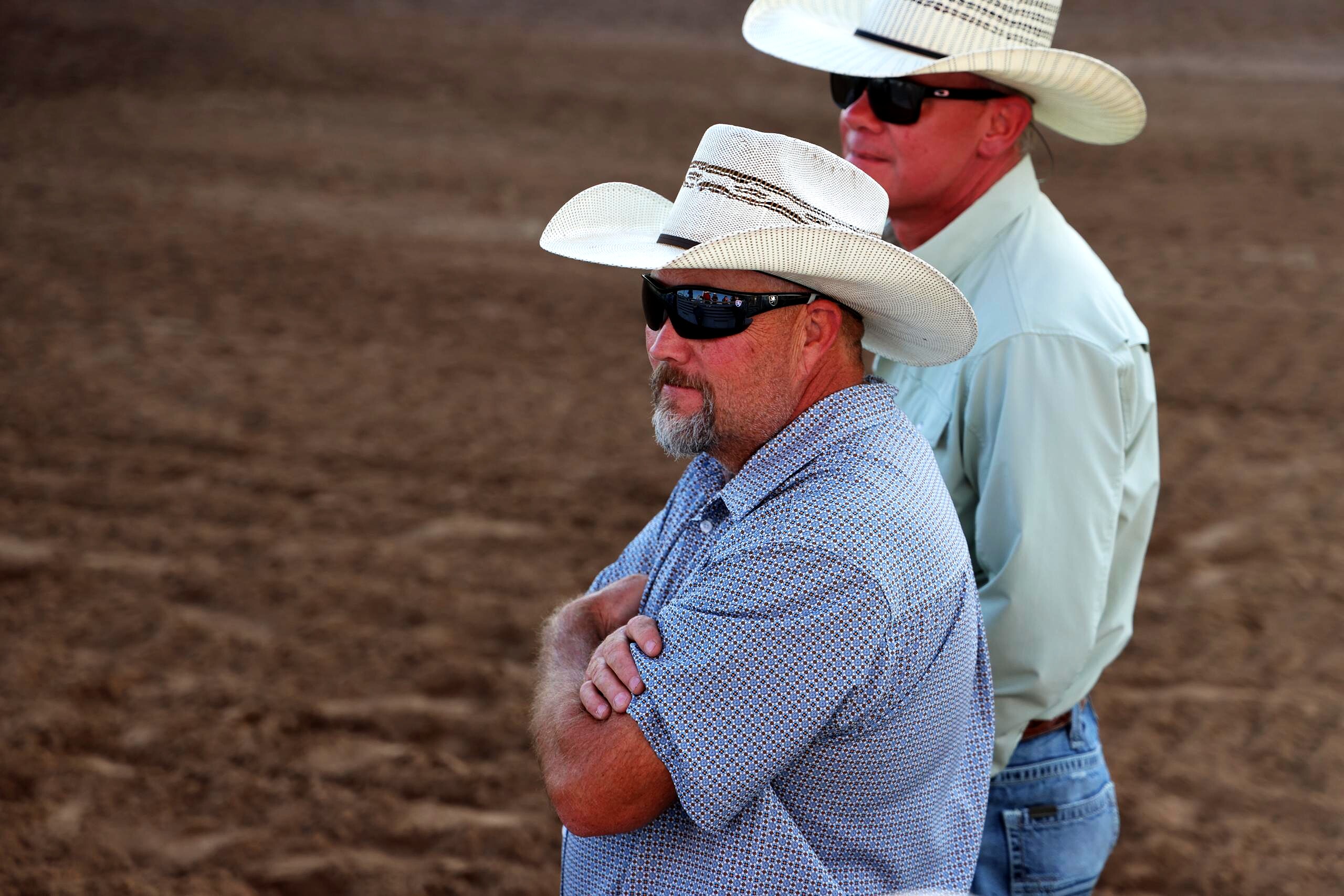 Two men in white cowboy hats watching the arena