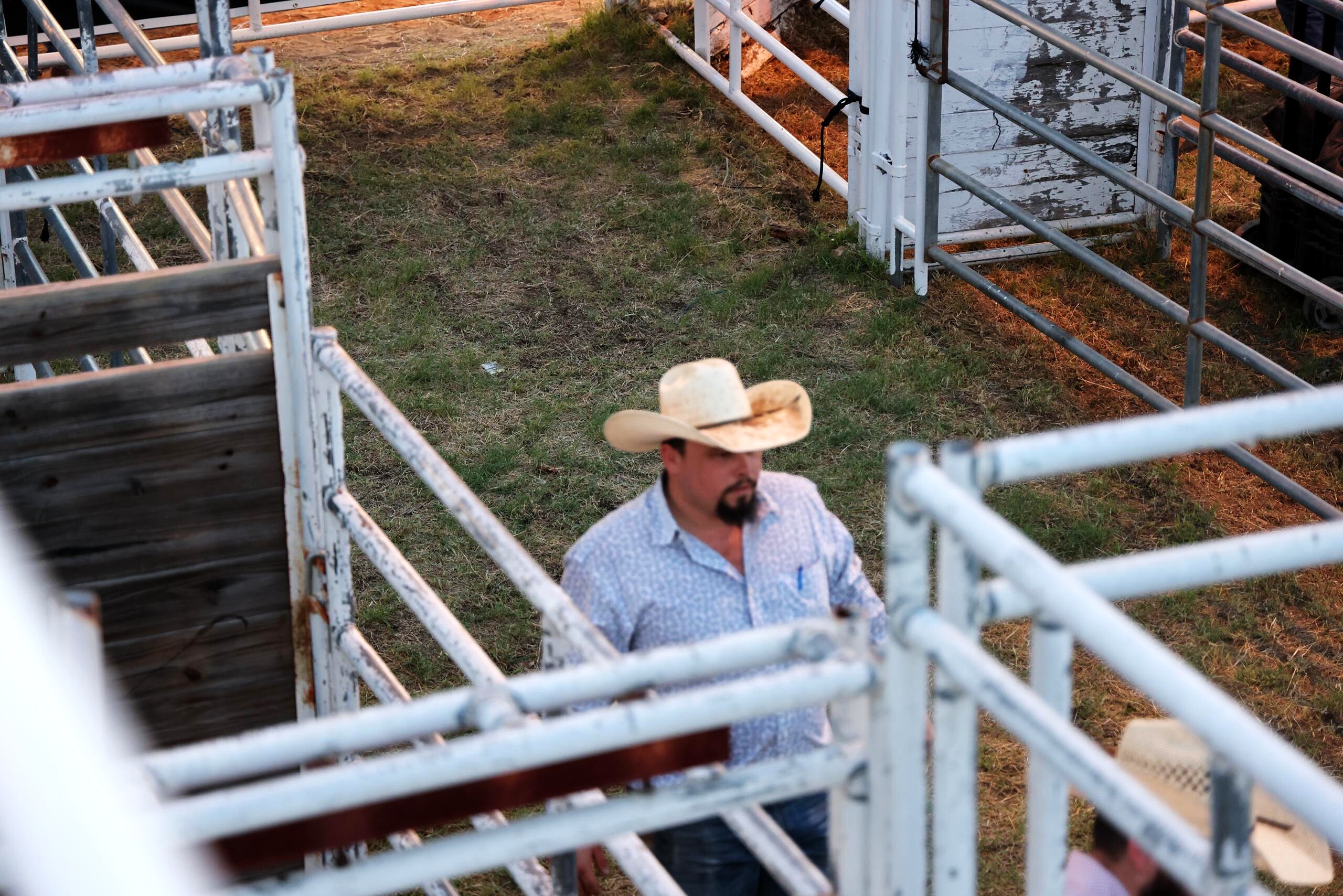 Man in a cowboy hat walking through the arena pens from above