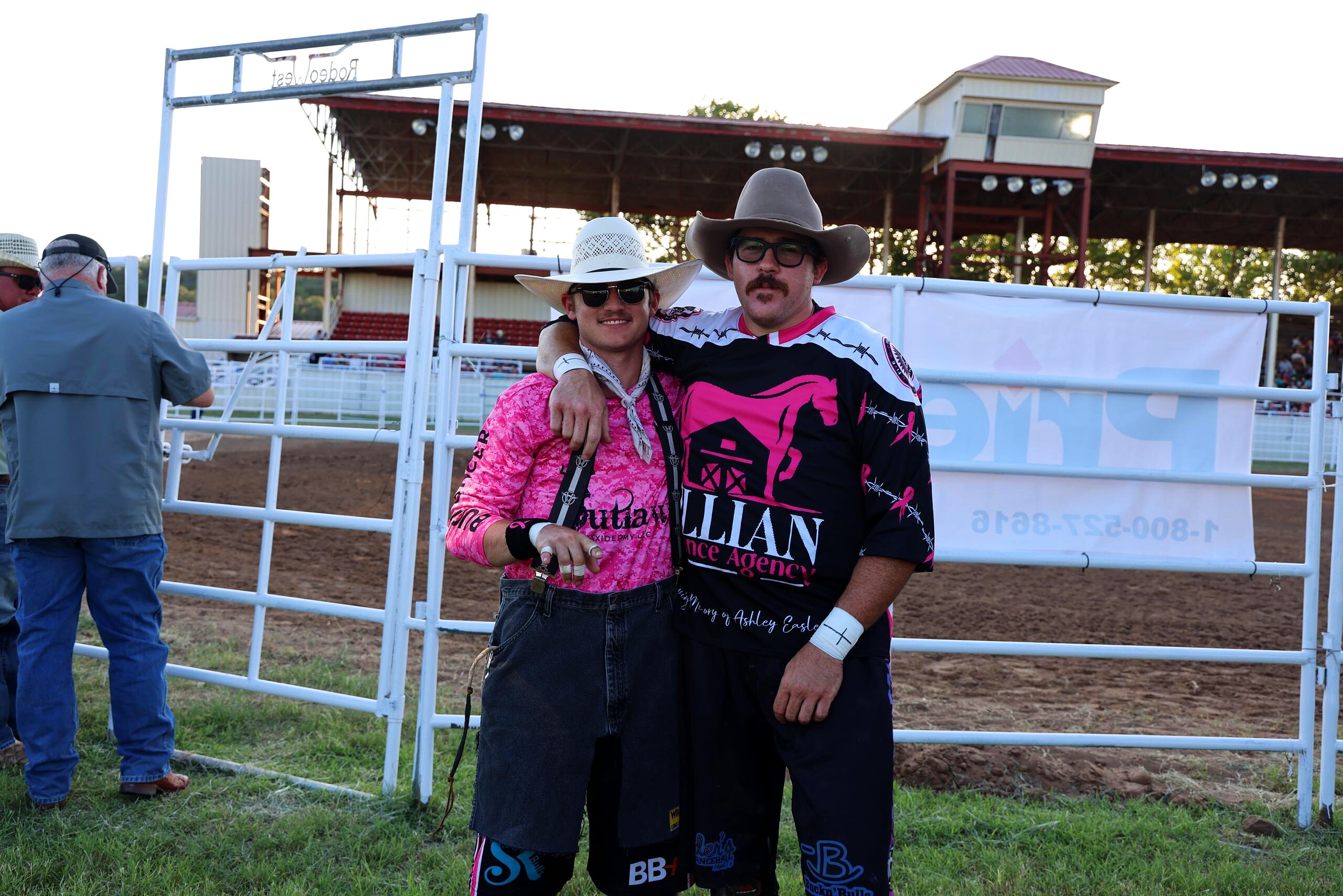 Two young rodeo participants posing by the arena fence