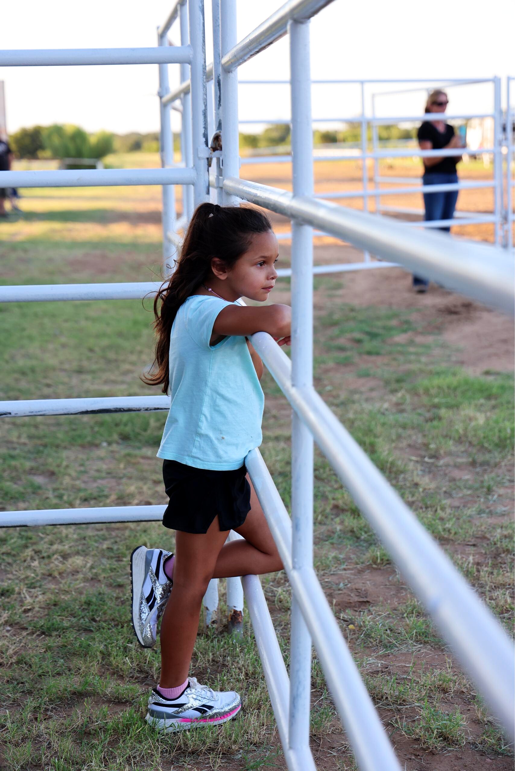 Young girl watching the rodeo from the arena fence