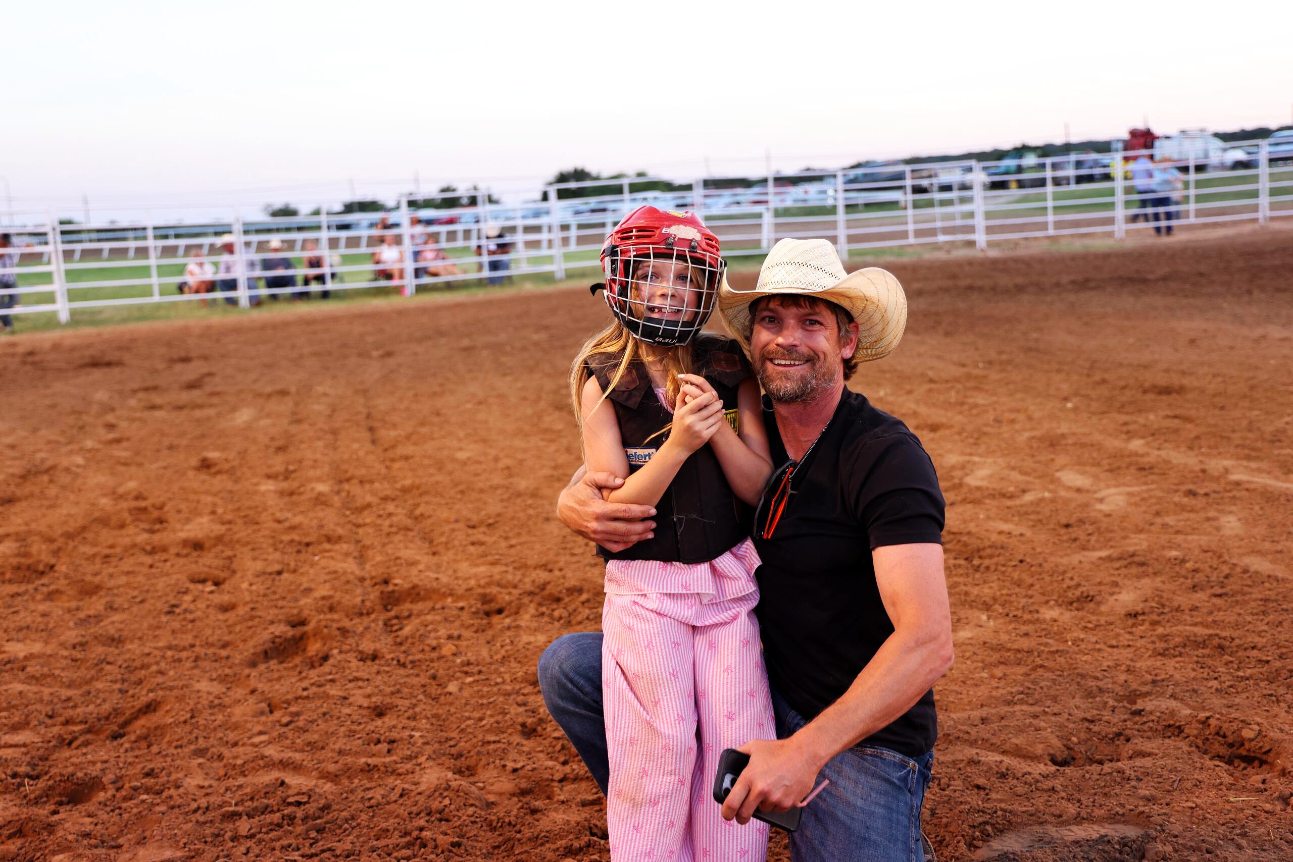 Young rider and adult kneeling together in the arena after a ride