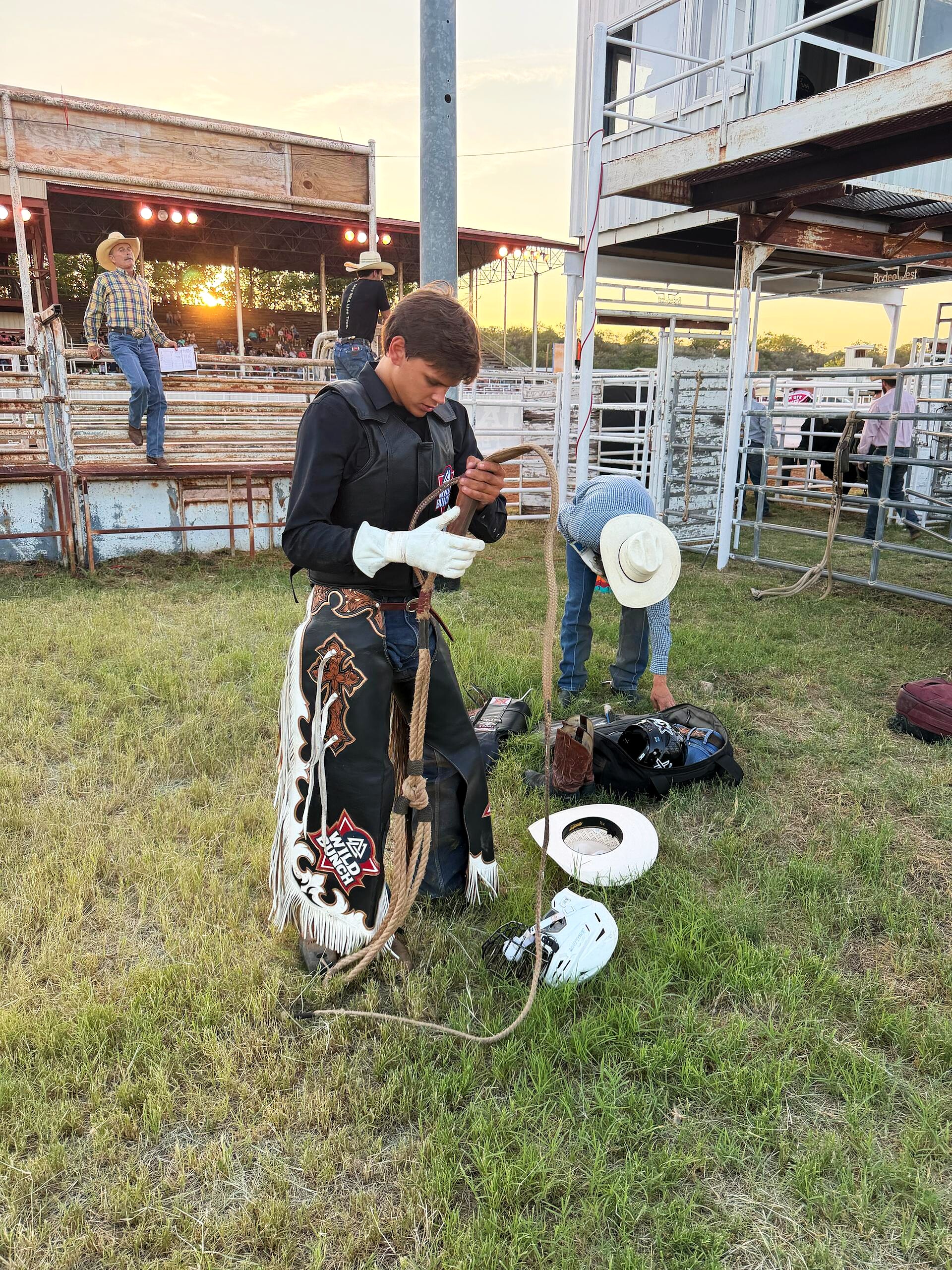 Bull rider preparing gear near the arena at sunset